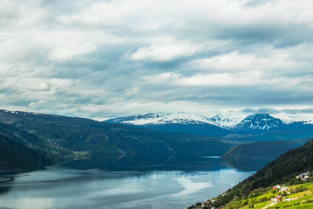 pexels photo 713074 713074 Breathtaking landscape of snow-capped Norwegian mountains and a tranquil lake reflecting the cloudy sky.